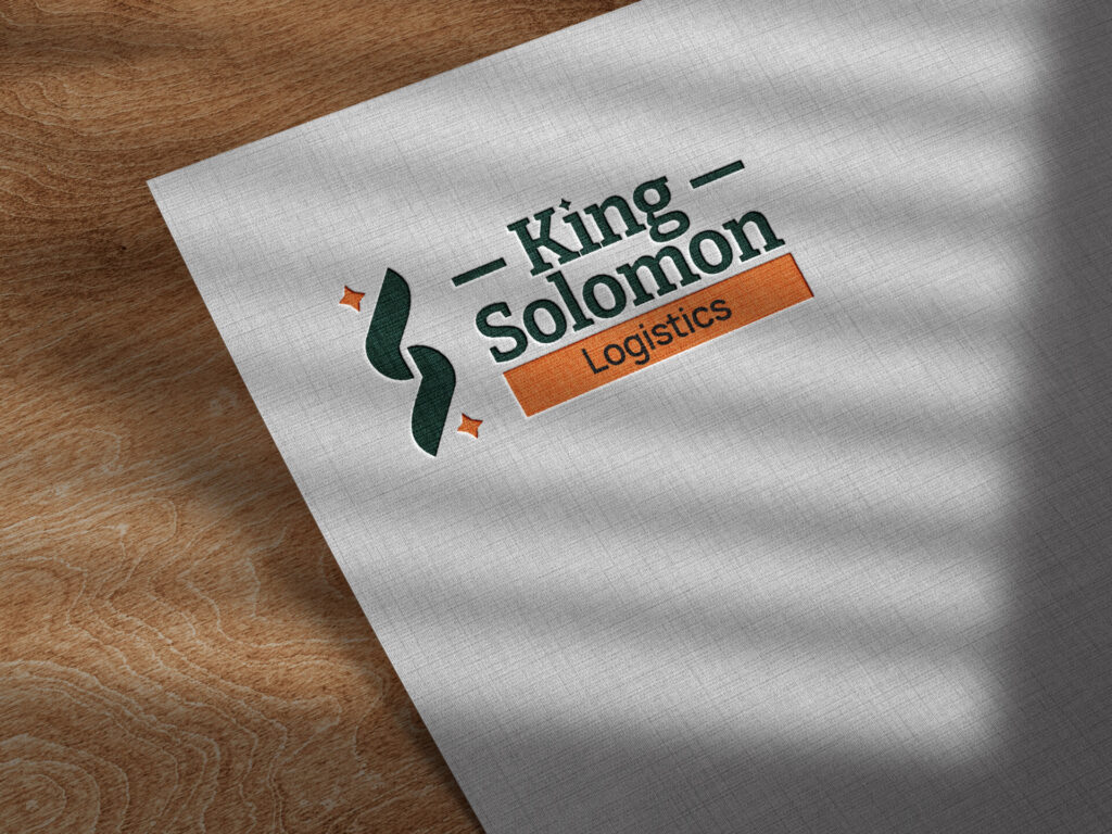 A piece of paper on a wooden surface shows a logo with the text "King Solomon Logistics," accompanied by abstract design elements in green and orange. Shadows from blinds cast a pattern of lines on the paper, creating a dynamic visual effect perfect for highlighting branding elements.